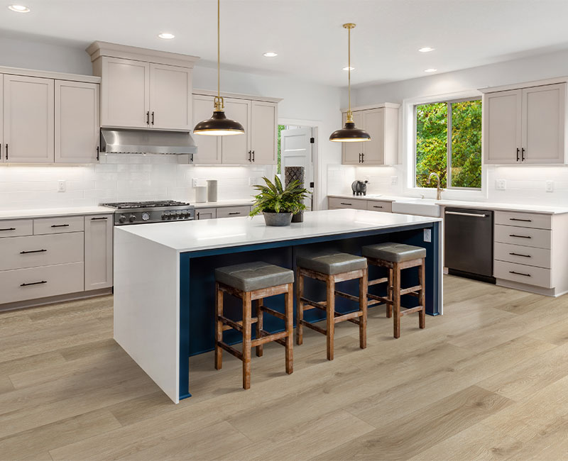 light hardwood flooring in kitchen with cream cabinets and white stone island with wood stools.